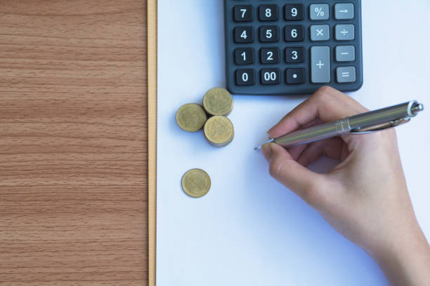 istock Businesswoman writing and analyzing for business with stack coins on the table. Financial analyzing and success concept. 899938580