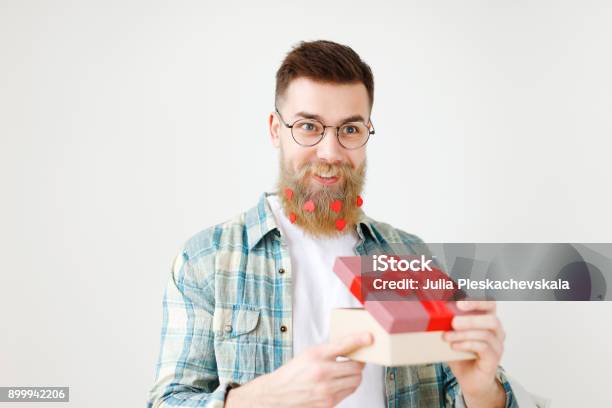 Fashionable Bearded Hipster Guy In Eyewear Opens Wrapped Present Recieves Surprise From Wife Being In Good Festive Mood Isolated Over White Background People Surprisment And Presents Concept Stock Photo - Download Image Now