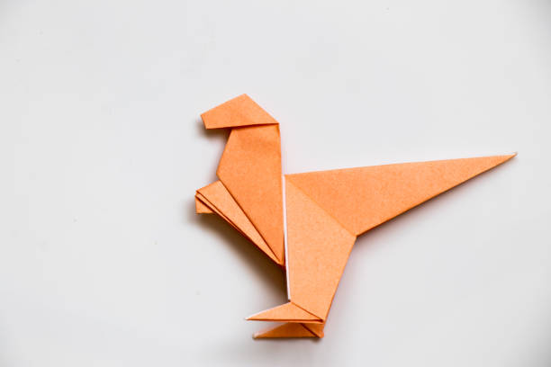 istock Origami orange paper fold as raptor dinosaur on white background 899951570