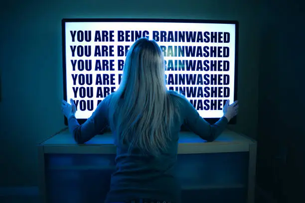 A woman stares at her television set as she is being brainwashed by it.