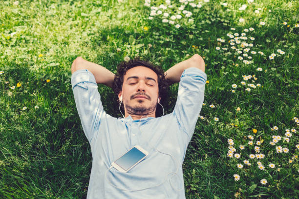 Man napping in the grass Relaxed man lying down at the meadow and listening to music meadow grass stock pictures, royalty-free photos & images