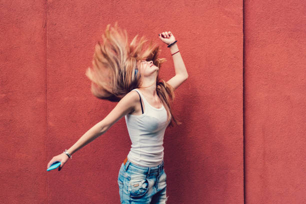 Girl shaking head to music Teenage girl dancing to the music against red wall young cool girl stock pictures, royalty-free photos & images