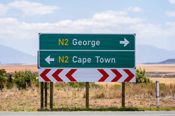 Road sign at the route N2 road in South Africa near Still Bay pointing to Cape Town and George. The N2 is a national route that runs from Cape Town to Ermelo and is the main highway along the ocean. Road sign at the route N2 road in South Africa near Still Bay pointing to Cape Town and George. The N2 is a national route that runs from Cape Town to Ermelo and is the main highway along the ocean. george south africa stock pictures, royalty-free photos & images