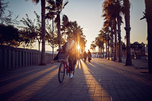 chica joven con bicicleta es disfrutando del atardecer en el paseo de la playa - women sunglasses little girls glamour fotografías e imágenes de stock