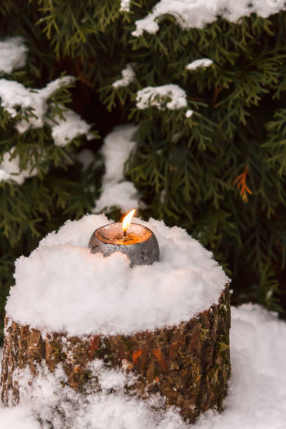 istock Burning candle on snow-covered stump in the open air 900009500