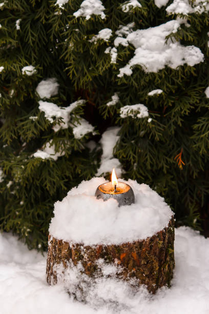 istock Burning candle on snow-covered stump in the open air 900011748