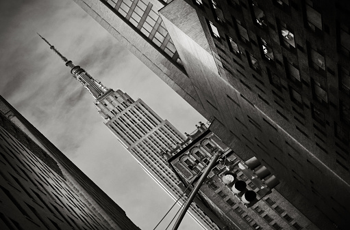 Monochrome abstract Empire State building framed by nearby buildings at a junction with traffic lights