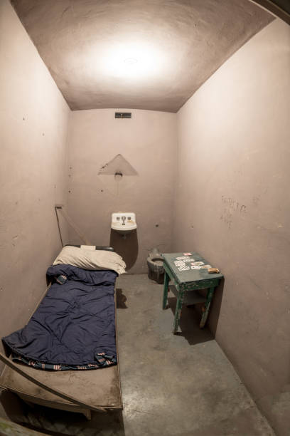 istock Small Jail cell with bed and playing cards 900024748