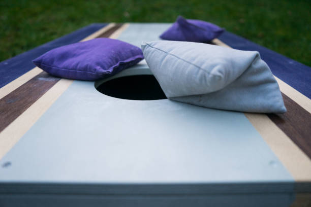 Purple Cornhole Bean Bag Toss Game Cornhole beanbag toss wood game board outside on grass bean bag stock pictures, royalty-free photos & images