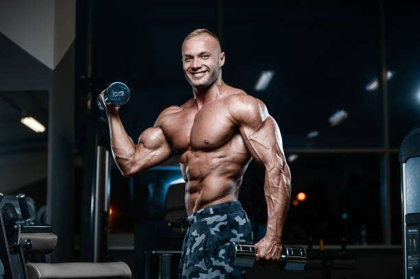 istock Brutal strong bodybuilder athletic men pumping up muscles with dumbbells 900033542