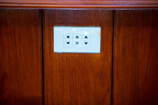 Focus white plug socket 3 chanels on the wood wall. electricity for house and city. charging energy concept. image for background, copy space.