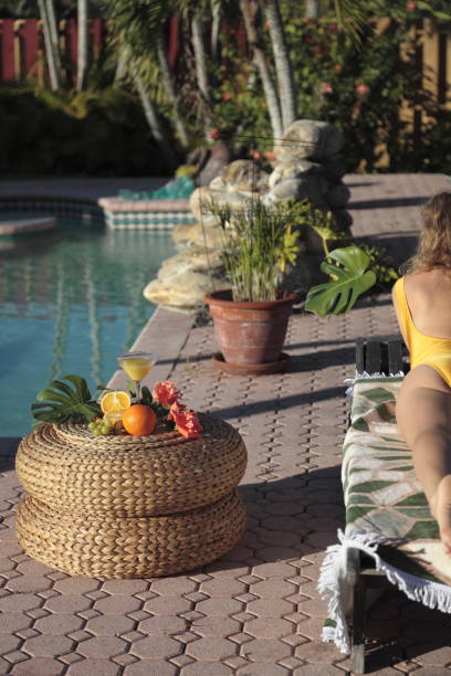 mulher tomando banho de sol junto à piscina. - full length florida tropical climate residential structure - fotografias e filmes do acervo
