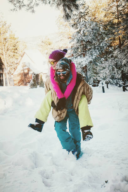 hombre caminando a través de nieve profunda con la mujer de espaldas - snowboard non urban scene woods snowboarding fotografías e imágenes de stock