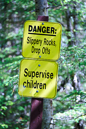 Danger slippery rocks, drop offs and supervise children sign.