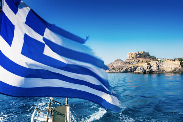 istock Greek flag and Lindos acropolis in background from boat deck (Rhodes, Greece) 900071410