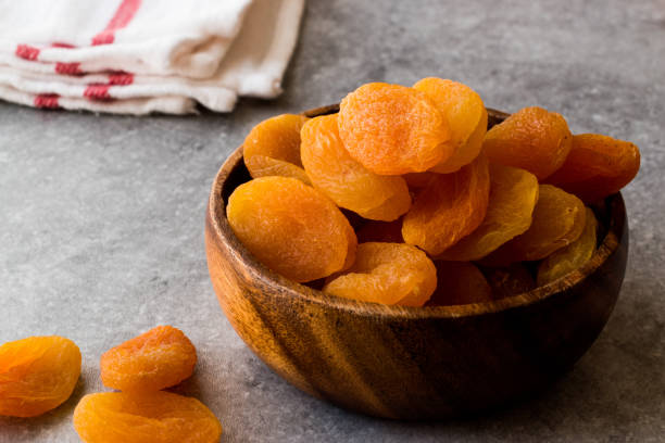 Dried Apricots in wooden Bowl. Dried Apricots in wooden Bowl. Organic Food. apricot stock pictures, royalty-free photos & images