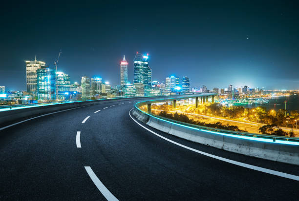 Blue neon light design highway overpass with modern city background . Night scene .