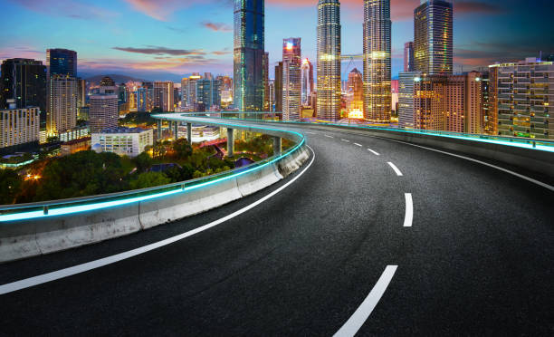 istock Blue neon light design highway overpass with modern city background . Twilight evening scene . 900114232