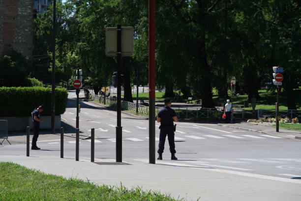 Police officers on the Critérium du Dauphiné in Grenoble Grenoble, France – June 10, 2017: photography depicting policemen blocking a street and ensuring the security and safety during the cycling event "Le Critérium du Dauphiné 2017". The photography was taken while attending Le Critérium du Dauphiné 2017 from the street of the city of Grenoble, France. riot police stock pictures, royalty-free photos & images