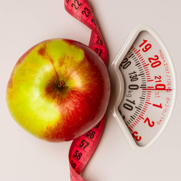 istock Apple with measuring tape on weight scale. Dieting 900172852
