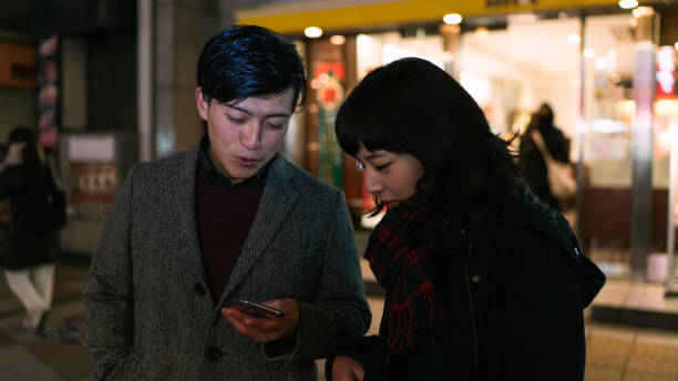 istock Young couple looking at smartphone together at night 900175990