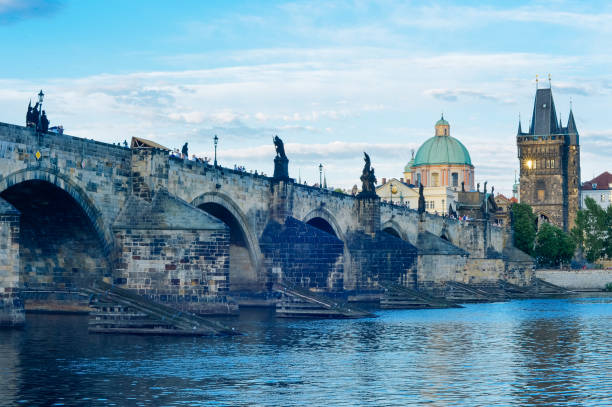 Charles Bridge is a historic bridge that crosses the Vltava river in Prague, Czech Republic. Its construction started in 1357 under the auspices of King Charles IV, and finished in the beginning of the 15th century.