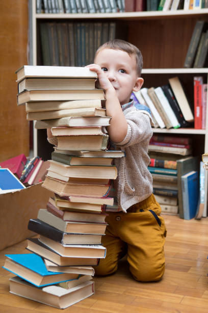 istock preschooler little boy reading a book in the library 900177068