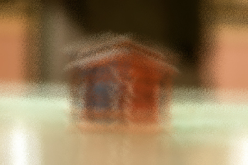wooden cottage shaped paper weight on the glass table. Concept of Own Home.Shot with frosted glass effect.
