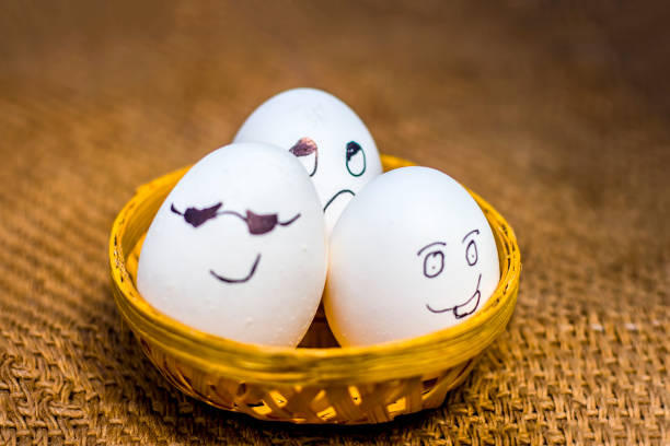 istock Funny faces drawn on the eggs which are in a traditional basket. 900180482