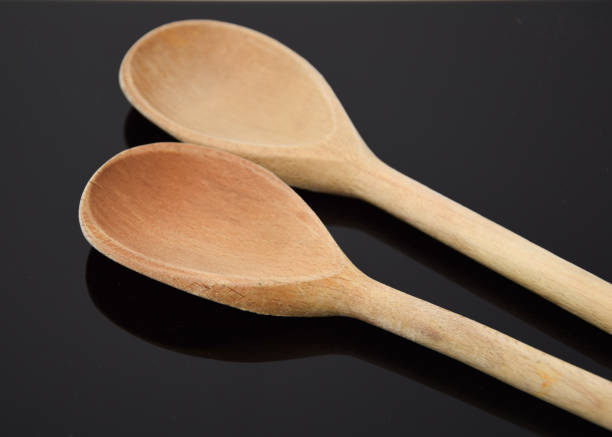 istock A pair of wooden spoons on a reflective black surface 900185684