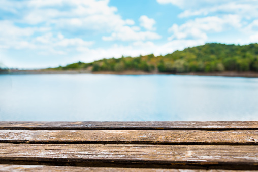 Close view of an old wooden table. Blue lake and sky in the background.