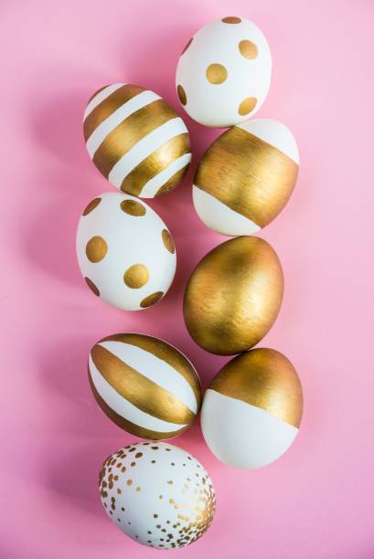 istock Top view of easter eggs colored with golden paint. Various striped and dotted designs. Pink background. 900189674