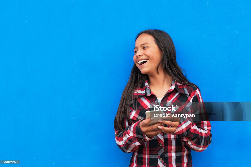 Portrait of beautiful latino girl using the mobile in the street. Portrait of beautiful latino girl using the mobile in the street. Childhood Concept. Latin American and Hispanic Ethnicity Stock Photo