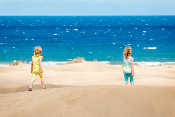 2 girls walk through the dunes to the beach by the sea