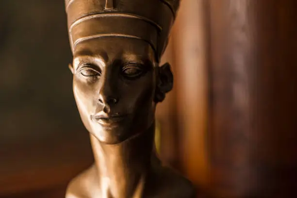 Photo of Close-up of a bronze colored Nefertiti bust, made with plaster.