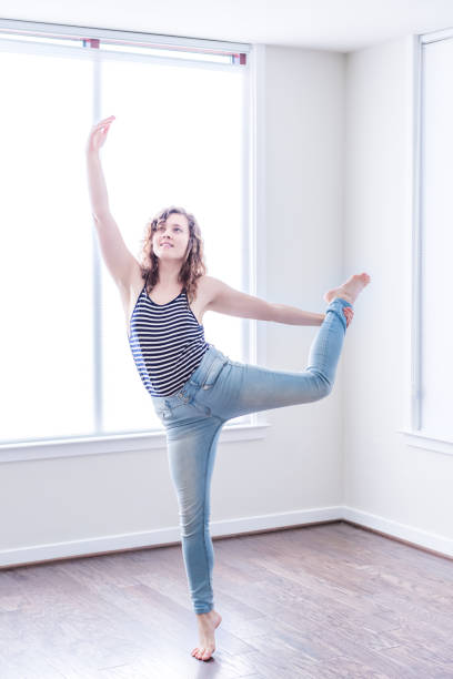 jovem mulher feliz dançando no quarto vazio de novo moderno, com pisos de madeira e grandes janelas ensolaradas no apartamento de alongamento - 5428 - fotografias e filmes do acervo