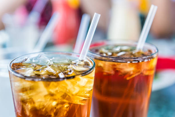 Macro closeup of iced tea or soda with ice cubes and straw in glass stock photo