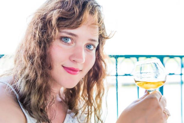 closeup retrato de una mujer joven sonriente feliz con bebida alcohólica ron bourbon en la mano por el agua en el restaurante de verano - mejillas enrojecidas fotografías e imágenes de stock
