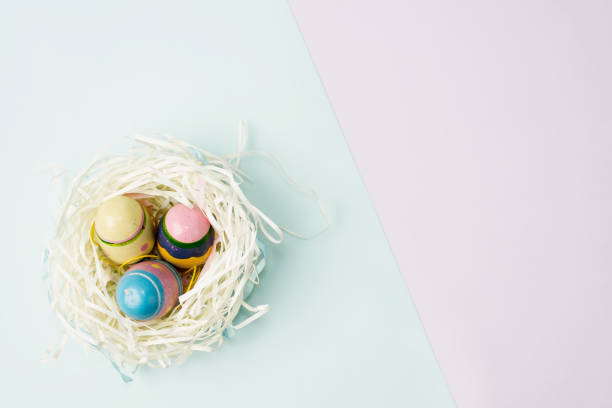 istock Flat lay top view paper nest with three vintage Easter eggs on blue and violet background 900212670