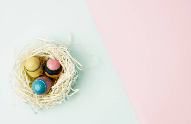Flat lay top view paper nest with three vintage Easter eggs on blue and pink background