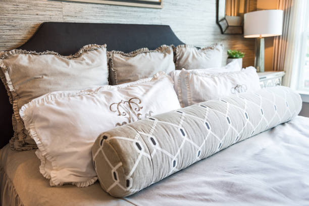 istock Closeup of new bed comforter with decorative pillows in bedroom in staging model home apartment or house 900212708