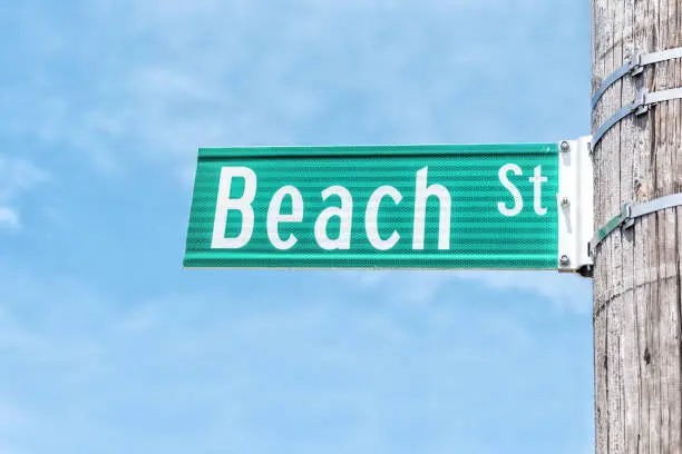 Closeup of Beach street sign attached on pole isolated against blue sky background
