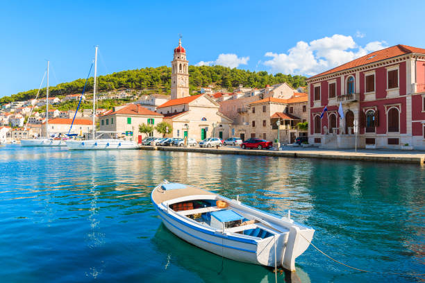 Fishing boat in Pucisca port with beautiful church in background, Brac island, Croatia Dalmatia is a narrow belt of the east shore of the Adriatic Sea, stretching from island of Rab in the north to the Bay of Kotor in the south. old catholic church on island brac croatia stock pictures, royalty-free photos & images