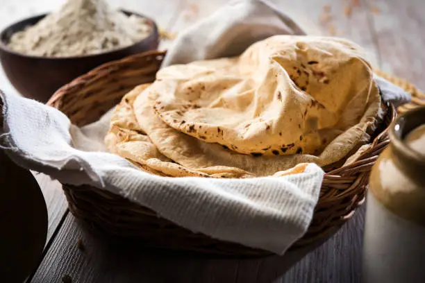 indian bread / Chapati / Fulka / Gehu Roti with wheat grains in background. It's a Healthy fiber rich traditional North/South Indian food, selective focus