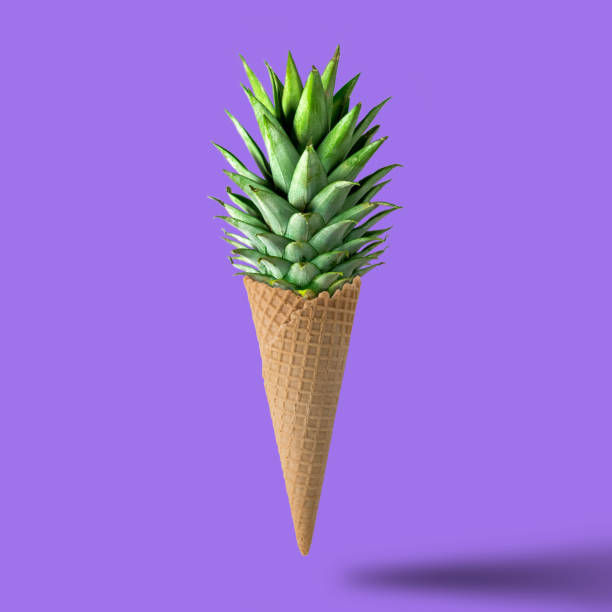 istock Ice cream cone with pineapple leaves on bright purple background. Fruit and candy concept. 900238758