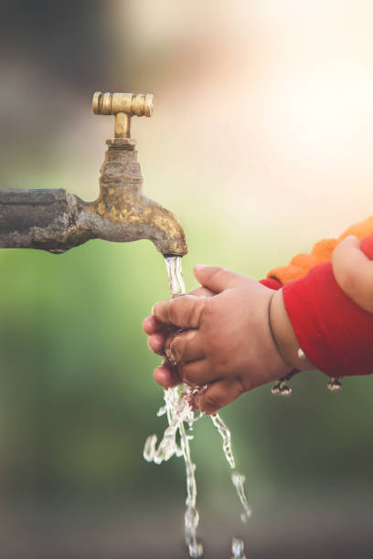 istock Stream of clean water pouring into infant hands. 900259362