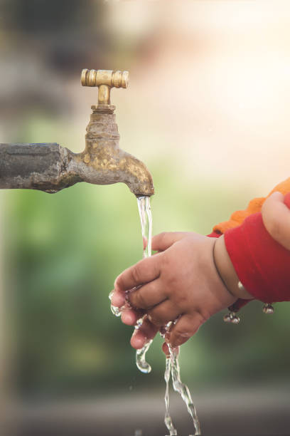 istock Stream of clean water pouring into infant hands. 900265528