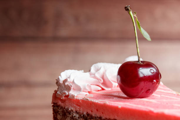 Chocolate cake with cherries on wooden background.