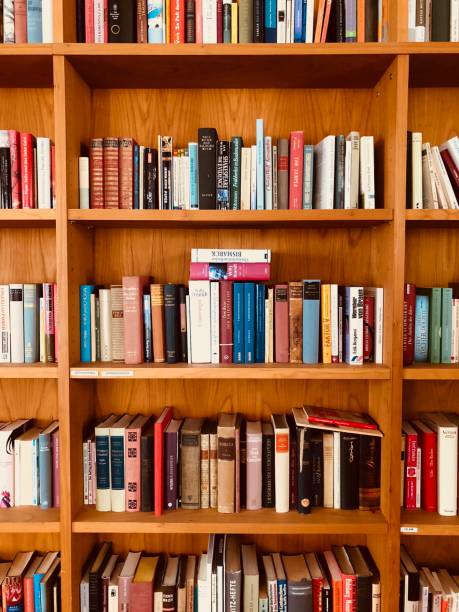 istock Brown wooden shelfs fully packed with books in a library 900284870