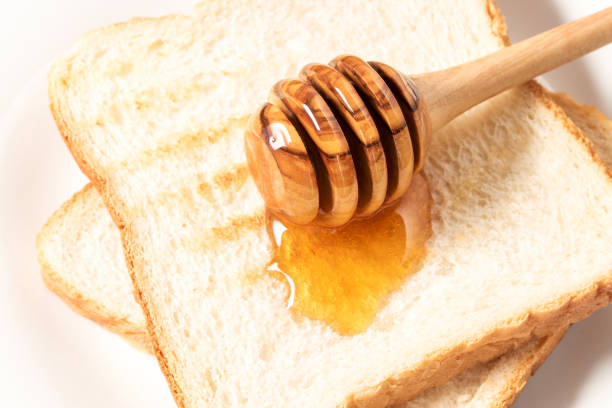 Honey with stick pouring over toast bread